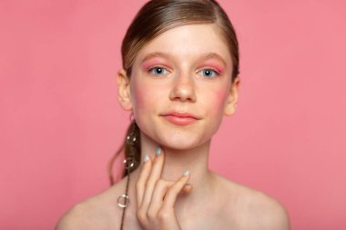 Tarafsız ifade, pembe arkaplan ve temiz cilt konseptine sahip minimal vesikalık fotoğraf.