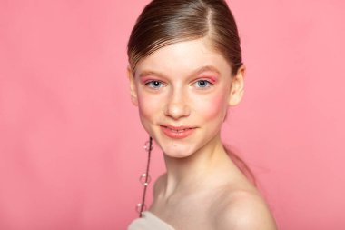 Gülümseyen güzel portre, yüzün yanındaki el, pembe üzerinde arkadaş canlısı genç ruh hali..