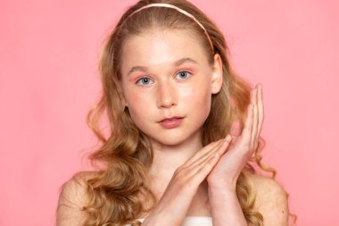 Pembe arka planda iki eli yüzü, derisi ve sağlık konsepti olan güzel bir portre..