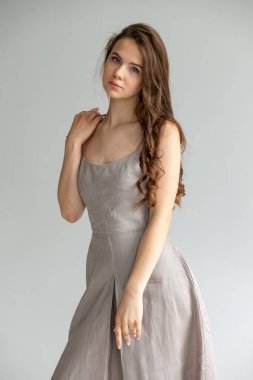 Yandan çıplak poz, nötr stüdyo arka planında minimalist editör portresi.