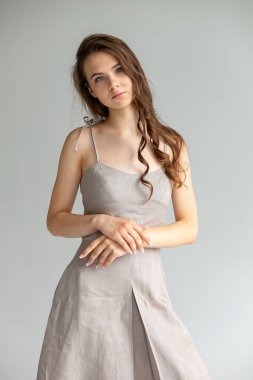 Tarafsız bir arkaplanda bej rengi slip elbiseli genç bir kadının tam vücut portresi..