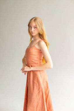 Full-length portrait in peach slip dress, calm minimal lifestyle fashion concept.