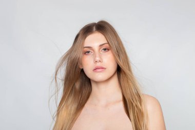 Studio portrait with calm expression, long hair and clean editorial style on gray.