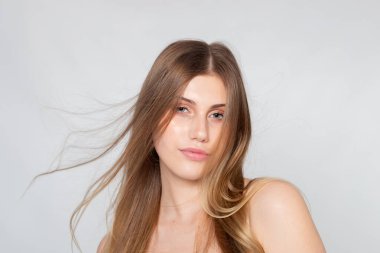 Saç hareketi vesikalığı, rüzgârlı teller, gri arka planda tertemiz stüdyo portresi..