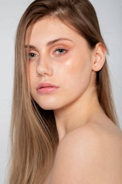 İnce röfleli minimal güzellik portresi, gri arka planda sakin güven.