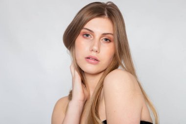 Yumuşak ifadeli, çıplak omuzlu, temiz arka planlı yakın portre.