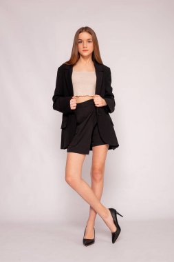 Stüdyo fotoğrafı, siyah ceket ve topuklu ayakkabı, modern güç giyinme konsepti..