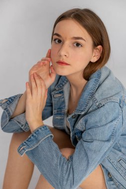 Close-up portrait, denim jacket styling, calm confidence and minimal background.