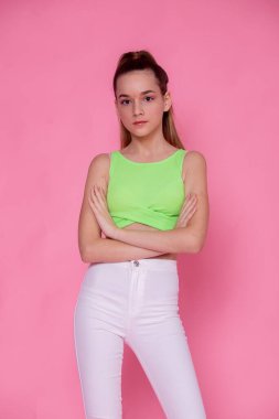 Pembe üzerine yarı vücut portresi, neon yeşil üst, kollar çapraz, kendinden emin modern moda..