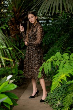 Eğreltiotu ön planda tam vücut portresi, sakin ifade, botanik yaşam tarzı estetik.