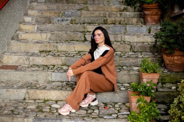 Yeşilliğe yakın basamaklarda oturan bir kadın, rahat Avrupa seyahati havası, İtalya yaşam tarzı.