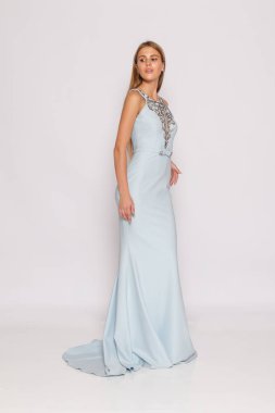 Full-length studio portrait of elegant woman in light blue evening gown, minimal white background, fashion lookbook style.