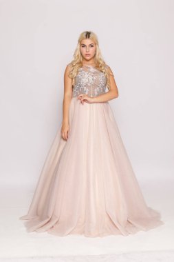 Şeftali rengi balo elbisesi, zarif poz, balo ya da nedime elbisesi konsepti giymiş sarışın manken..