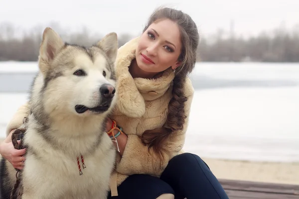 Jovem mulher com cão lobo na neve — Fotografia de Stock