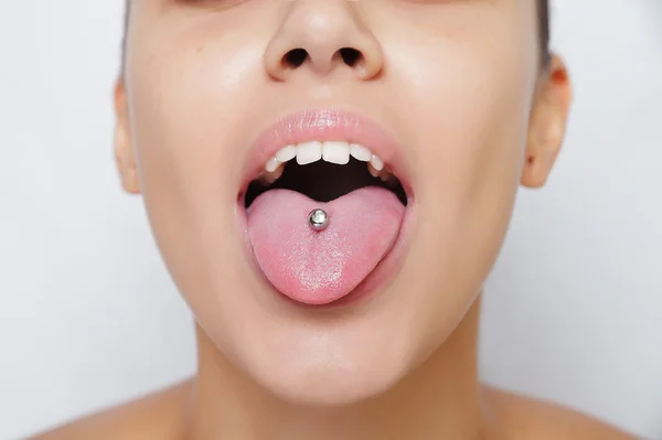 Krásná žena, trčí jí jazyk a ukazovat mladým piercing — Stock fotografie