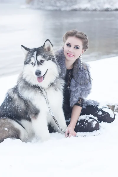 Ung kvinna med varg hund i snö — Stockfoto