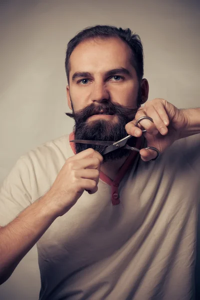 Bărbat tăiere barbă pe un fundal gri — Fotografie, imagine de stoc