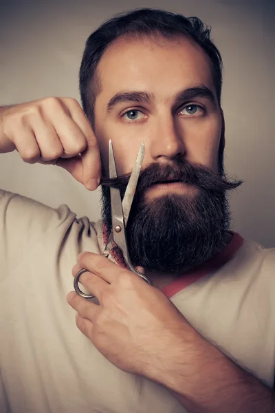 Człowiek cięcia brodę na szarym tle — Zdjęcie stockowe