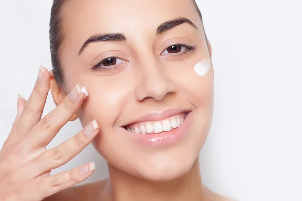 Красивая модель нанесения косметического крема лечение на ее лицо белое — стоковое фото