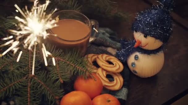 Tangerines and cinnamon stick, lit sparkler on vintage wooden background — Stock Video
