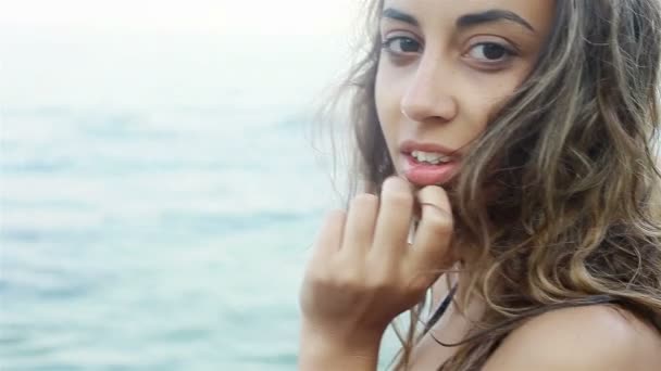 Outdoor fashion portrait of sexy brunette woman athletic girl posing with a view of the sea, slowly.  in a blue bathing suit, sunny day. — Stock Video