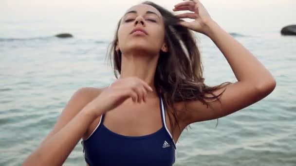 Outdoor fashion portrait of sexy brunette woman athletic girl posing with a view of the sea, slowly.  in a blue bathing suit, sunny day. — Stock Video