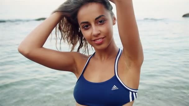 Ritratto di moda all'aperto di sexy ragazza bruna atletica in posa con vista sul mare, lentamente. in costume da bagno blu, giornata di sole . — Video Stock