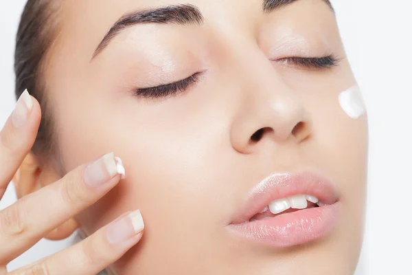 Mooi cosmetische crème behandeling toe te passen op haar gezicht wit model — Stockfoto