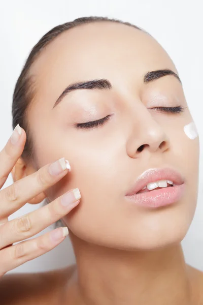 Hermosa modelo aplicando tratamiento de crema cosmética en su cara blanca — Foto de Stock