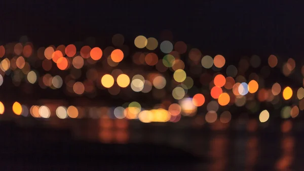 Blurred city lights over the water — Stock Photo, Image