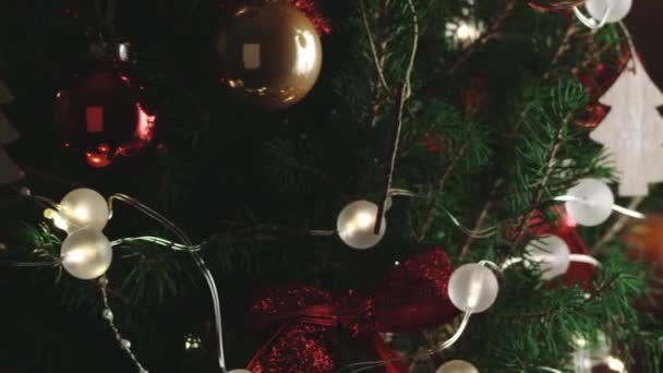 Christmas tree. New Years Christmas festive background. Decorations, red gold balls and glowing bulbs on the tree. Warm home mood. Depth of field, soft focus. Spinning. Close up. Red camera, 4K — Stock Footage Christmas tree. New Years Christmas festive background. Decorations, red gold balls and glowing bulbs on the tree. Warm home mood. Depth of field, soft focus. Spinning. Close up. Red camera, 4K Stock Footage