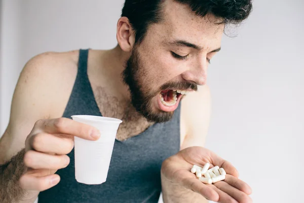 Zieke man met pillen geïsoleerd op een witte achtergrond — Stockfoto