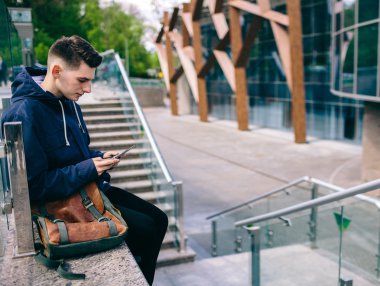 Yakışıklı cep telefonu şehir dışında, genç çekici öğrenci mavi gömlekli konuşuyor.