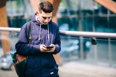Yakışıklı cep telefonu şehir dışında, genç çekici öğrenci mavi gömlekli konuşuyor.