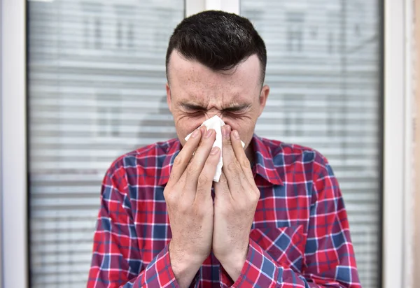 Фото молодого человека с платком. У больного нос насморк. делает лекарство от простуды — стоковое фото