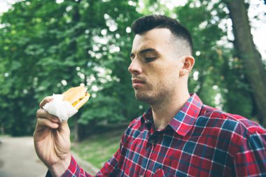 Adam parkta yemek yiyor ve lezzetli yemeklerin tadını çıkarıyor.