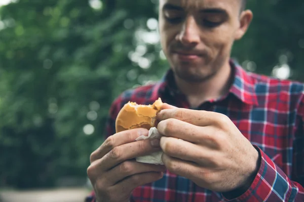 Mann isst im Park und genießt leckeres Essen — Stockfoto