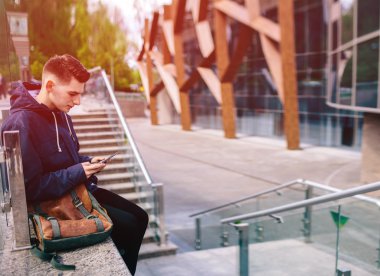 Yakışıklı cep telefonu şehir dışında, genç çekici öğrenci mavi gömlekli konuşuyor.