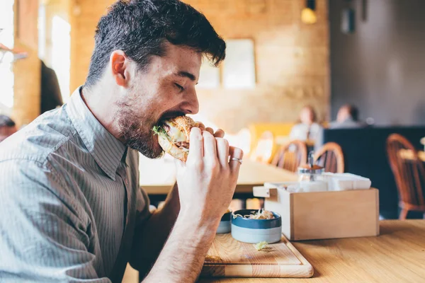 El hombre está comiendo en un restaurante y disfrutando de deliciosa comida —  Fotos de Stock