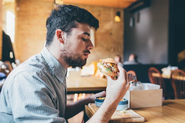 Homem está comendo em um restaurante e desfrutando de deliciosa comida — Fotografia de Stock