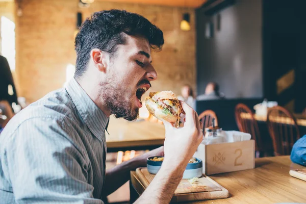 El hombre está comiendo en un restaurante y disfrutando de deliciosa comida — Foto de Stock