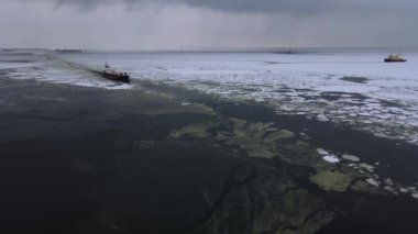 Denizdeki ultra büyük kargo gemisinin hava görüntüsü gün batımında limandan ayrılıyor. Tankerin arka tarafındaki insansız hava aracı görüntüleri. Ulaşım lojistiği, denizcilik kavramı.
