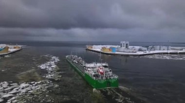 Yüksek hızda nakledilmek üzere büyük bir deniz kargo gemisi gün batımında mavi deniz alanını açmak için şehir limanından ayrılıyor. Malların deniz yoluyla ithalatı ve ihracatı. Lojistik. Deniz işleri..