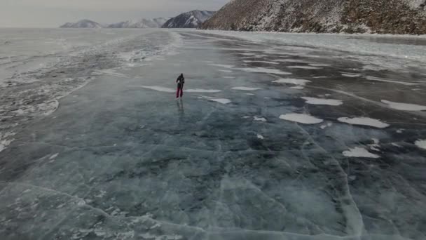 Baykal Gölü 'nde buz pateni. Adam donmuş Baykal Gölü 'nün buzunda kayıyor. Pürüzsüz mavi şeffaf buzla güzel bir kış manzarası — Stok video