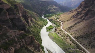 Yukarıdan dolambaçlı buzul nehrinin manzarası, dağlarla çevrili. Bir İHA 'dan havadan çekim.