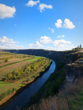 Tepedeki manastır. Dönen bir nehirle kesişen kayalık tepelerin güzel yüzeyi. Mavi gökyüzü ve beyaz bulutlarla güneşli bir gün. Raut Nehri, Old Orhei, Moldova.