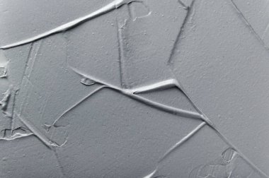 Yüz maskesi ve kozmetik ovalama dokusu yakından. Kadın hijyeni ve cilt bakımı. Akrilik boya fırça darbeleri arka planda. Güzellik ürünü, spa salonu prosedürü. Gri arkaplan için çamur maskesi.