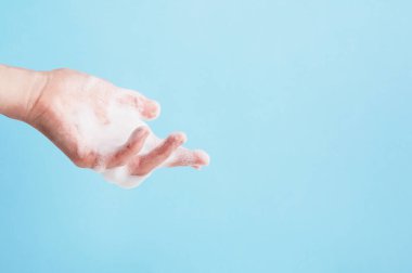 Elin beyaz sabun köpüğüyle kaplı. Yıkama ve hijyen. Temizlik ve banyo zamanı. Temizlik ve vücut bakımı kavramı. Sağ tarafta uzayı kopyala. Mavi üzerine izole edilmiş..