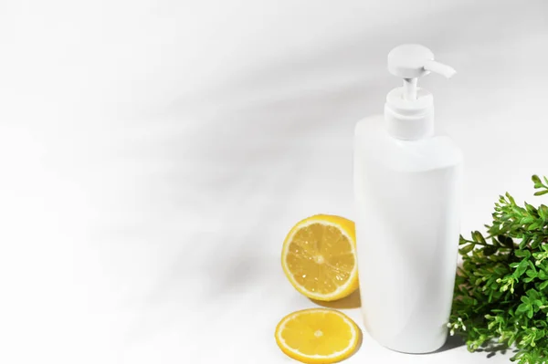 Frasco blanco sin marca con limón y plantas verdes. Contenedor con dispensador de productos cosméticos naturales. Flacon en blanco para loción, crema, loción corporal, champú o acondicionador capilar. Estilo de burla — Foto de Stock