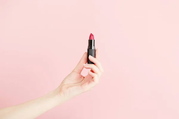 Ruj tutan kadın eli. Maquillage için ekipman. Makyaj ve vizör. Metin ya da yaratıcı tasarım için yer. Model stili. Kozmetik ve güzellik konsepti. Pembe üzerine izole edilmiş..